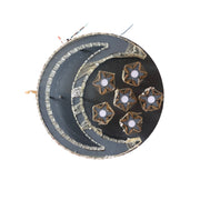 Decorative plate with star designs on a wooden stand against a corrugated metal background